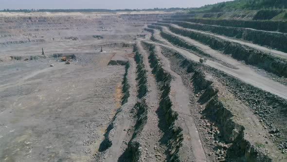 Mining Dump Trucks in Large Granite Open Pit Mine. Empty Truck Rides on Quarry Ledge Road