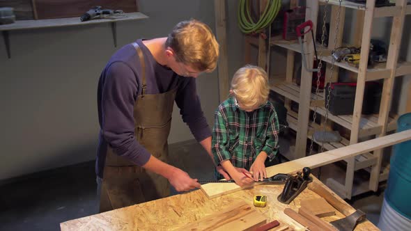 Man and Boy Work with Wood Board in the Workshop