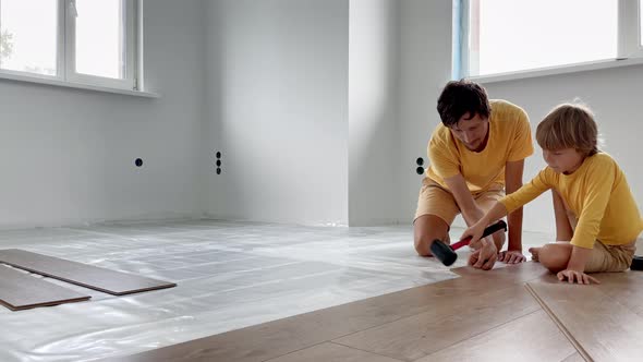 Father and His Little Son Install Laminate on the Floor in Their Apartment