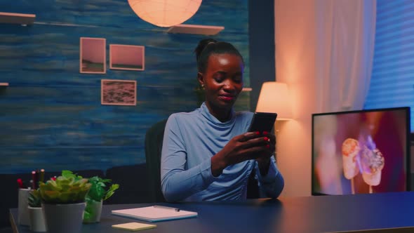 Black Businesswoman Browsing Using Smartphone Sitting in Living Room