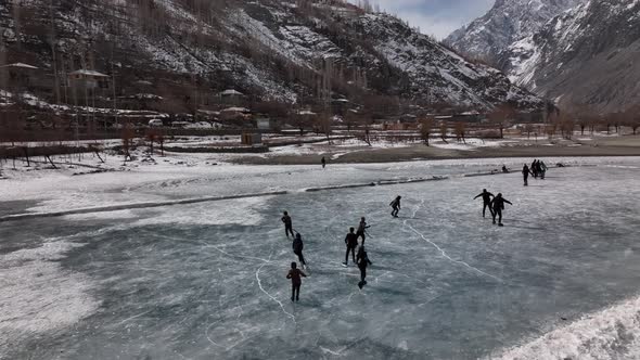 silhouette Of Ice Hockey Players On Frozen Khalti Lake At Ghizer Valley. High Angel Pan Right