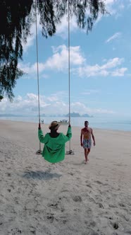 Couple Men and Woman at a Swing on the White Tropical Beach Phuket Thailand Naka Island