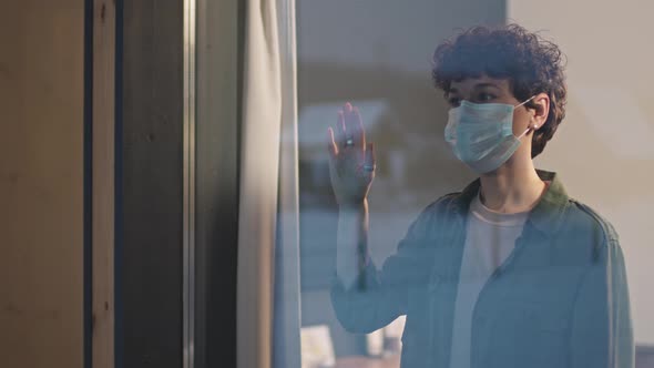 Sad Woman In Protective Mask Standing Near Window