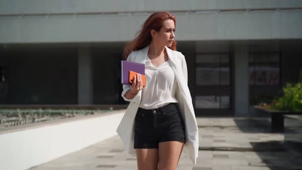 Beautiful business woman with notebook in her hands walk to office in heels work