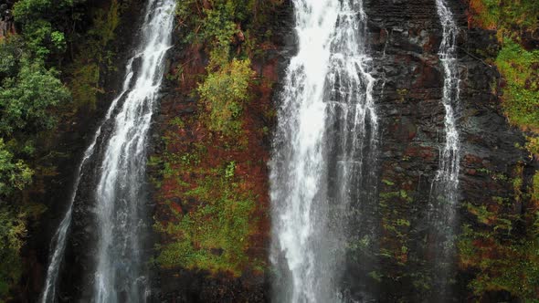 Drone rises above a high waterfall on a cliff at Opaekaa Falls, Kauai, Hawaii, USA