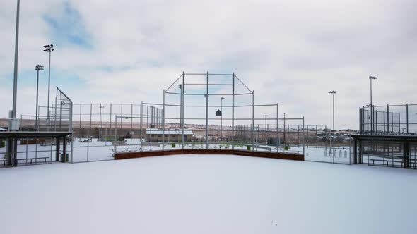 Reveal of baseball and softball diamond, pitchers mound, and dugouts with freshly fallen snow, aeria