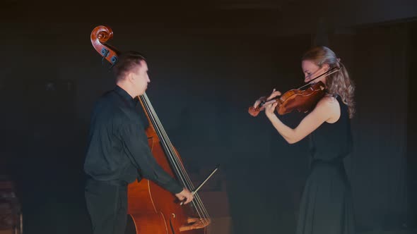 Professional Musicians Rehearse Classical Music Pieces on Violin and Cello on the Dark Stage