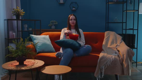 Woman Sitting on Sofa Alone Eating Popcorn and Watching Interesting Tv Serial Horror Film at Home