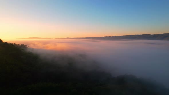 Aerial view of sunrise with fog above mountains