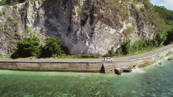 Aerial view of white car driving on coastline in Oslob, Philippines.