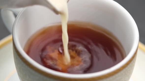Pouring Milk Into Cup with Tea