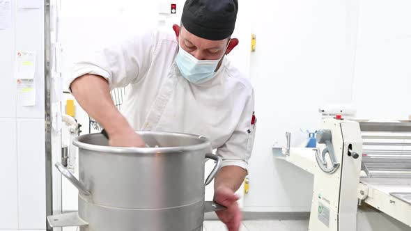 Skilled Pastry Chef Preparing Cake Cream in Interior of Modern Bakery Kitchen Wearing Protective