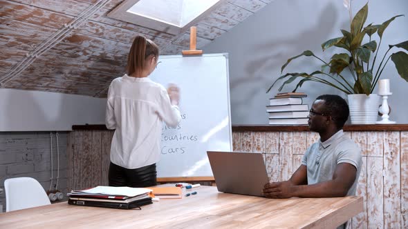 An English Lesson - Woman Cleaning the Board and a Black Man Sitting By the Table