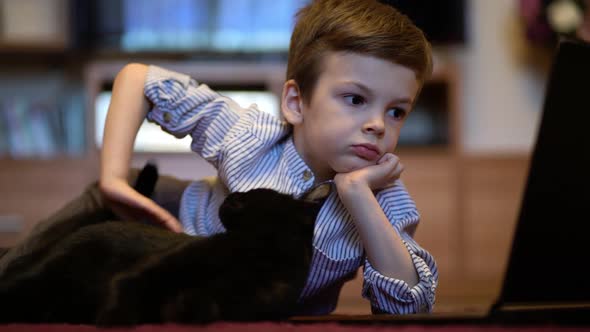 Funny Child with Kitten Using a Laptop at Home.
