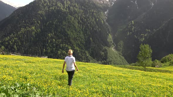 Blond Haired Woman Walks Alone in Meadow With Yellow Flowers in Forest