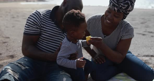African child having fun with mother and father on the beach - Black family enjoy summer time