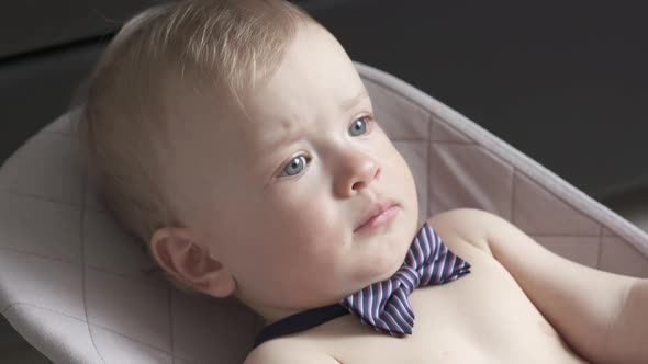 Cute Small Child Face Closeup One Year Old Baby Boy Wearing a Bow Tie Lying in Rocking Chair for