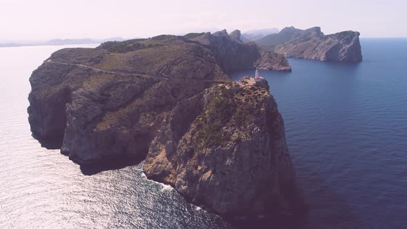 Lighthouse on rocky seashore with curved road