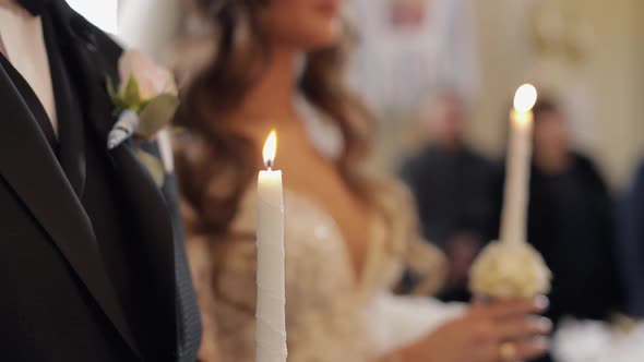 Newlyweds. Bride and the Groom Stand in Church, Holding Candles in Their Hands