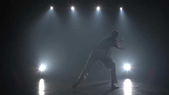 Powerful Men Practicing Capoeira in Darkness Against Spotlight in Studio.