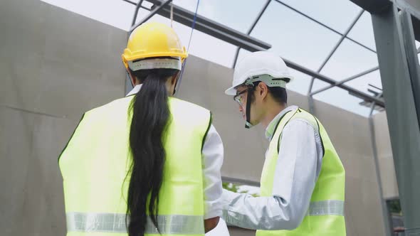 Asian construction workers people wear protective helmet hold drawing, work onsite of architecture.