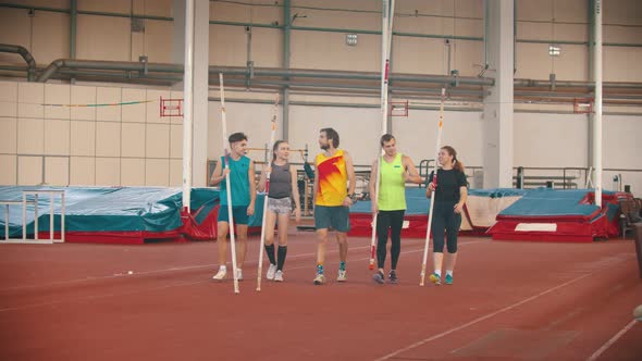 Group of Young Smiling People on the Pole Vault Training Walking on the Track