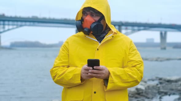 expert ecologist stands on the city river and writes a message on the phone.