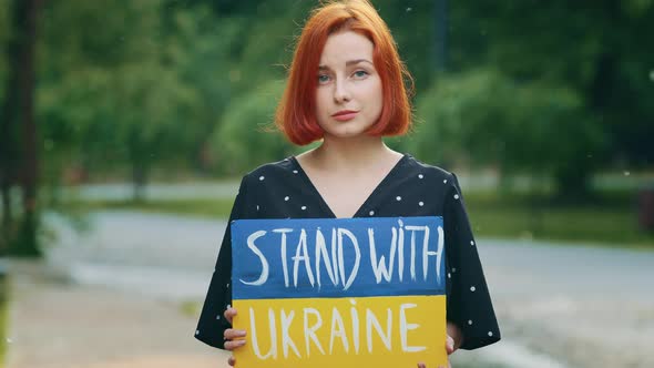 Sad Redhead Girl Hold Cardboard with Written Inscription Phrase Stand with Ukraine Shows Patriotic