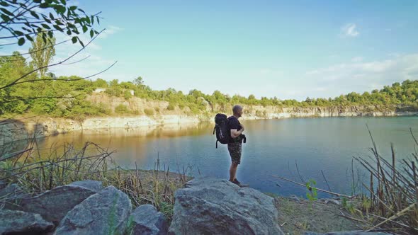 tourist with a backpack on his shoulders is looking at the colorful terrain by the river