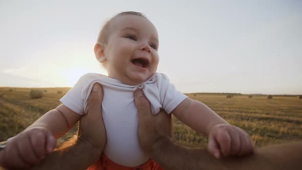 Young Dad Holds in the Hands of First Person in the Field