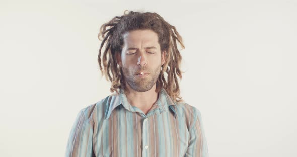 Man with dreadlocks smoking medicinal marijuana on white background