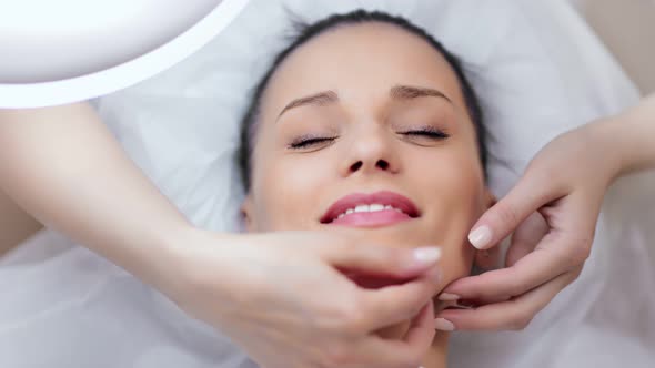 Closeup Smiling Adorable Young Woman Enjoying Facial Lifting Massage at Beauty Spa Salon