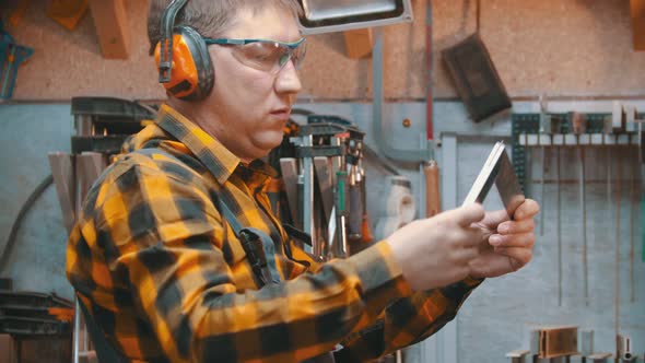 Carpentry Indoors - a Man Woodworker Takes a Yardstick From the Wall Rack