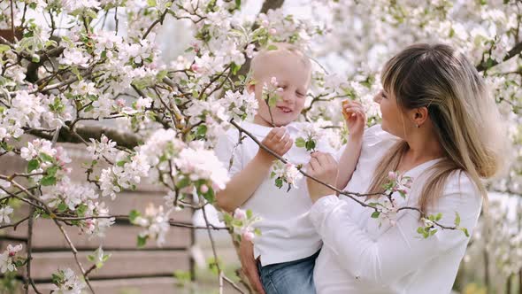 Mother and Little Son Standing Near Flowering Tree in Village