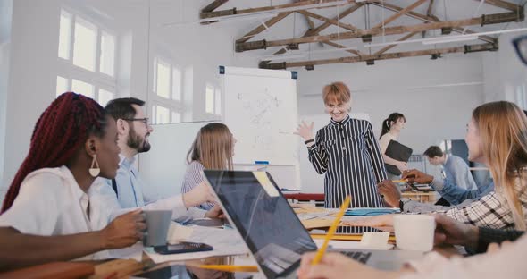 Young Attractive Caucasian Female Company Boss Giving a Motivation Speech, Laughing with Multiethnic