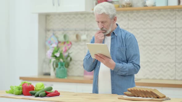 Old Man Using Tablet While Standing in Kitchen