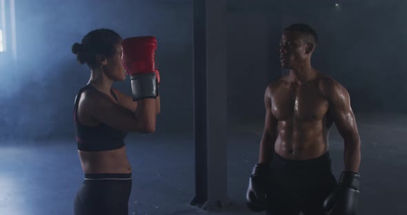 African american man and woman wearing boxing gloves training throwing punches in empty room