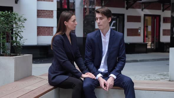 A young couple sit on a bench and communicate