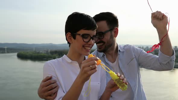 Romantic Young Couple Dating Outdoor and Blowing Bubbles