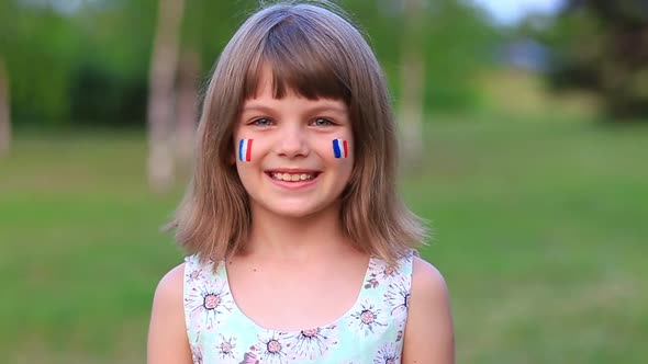 Adorable Little Girl Smile at Camera with Cheeks Painted in Flag of France