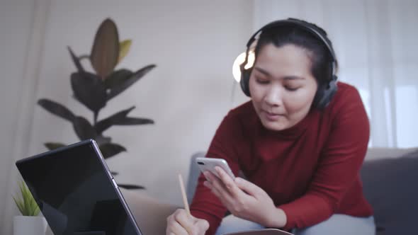 Freelance woman redshirt using tablet with headphone for meeting online at home