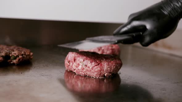 Smashing delicious burger meat with a spatula against a hot metal plate