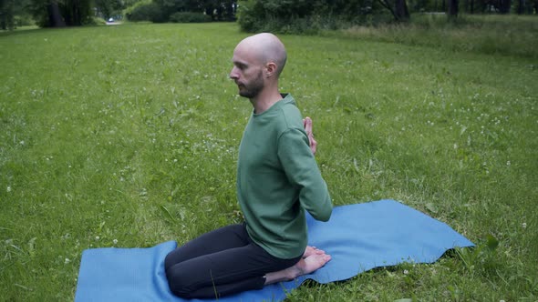 Man Does Yoga in His Garden on the Green Lawn