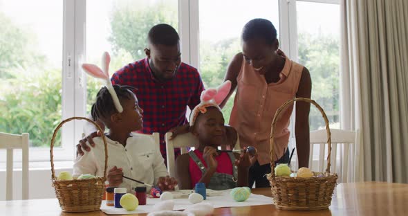 African american family painting easter eggs together at home