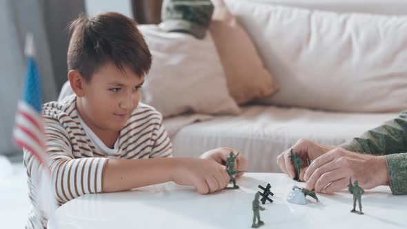 Boy and Unrecognizable Father Playing with Toy Soldiers