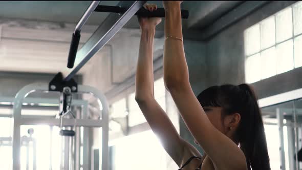 Strong Woman Doing Chin Ups Exercise on Bars at the Gym