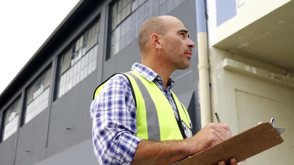 Construction worker writing on a clipboard