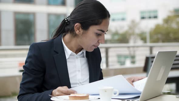 Businesswoman Using Laptop and Working with Papers