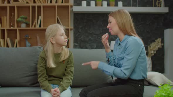 Cute School Age Hearing Impaired Daughter and Mother Sharing and Bonding on Sofa