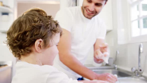 Son helping father in washing utensils